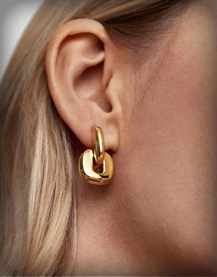 KAVNAR gold drop earrings on neutral background
